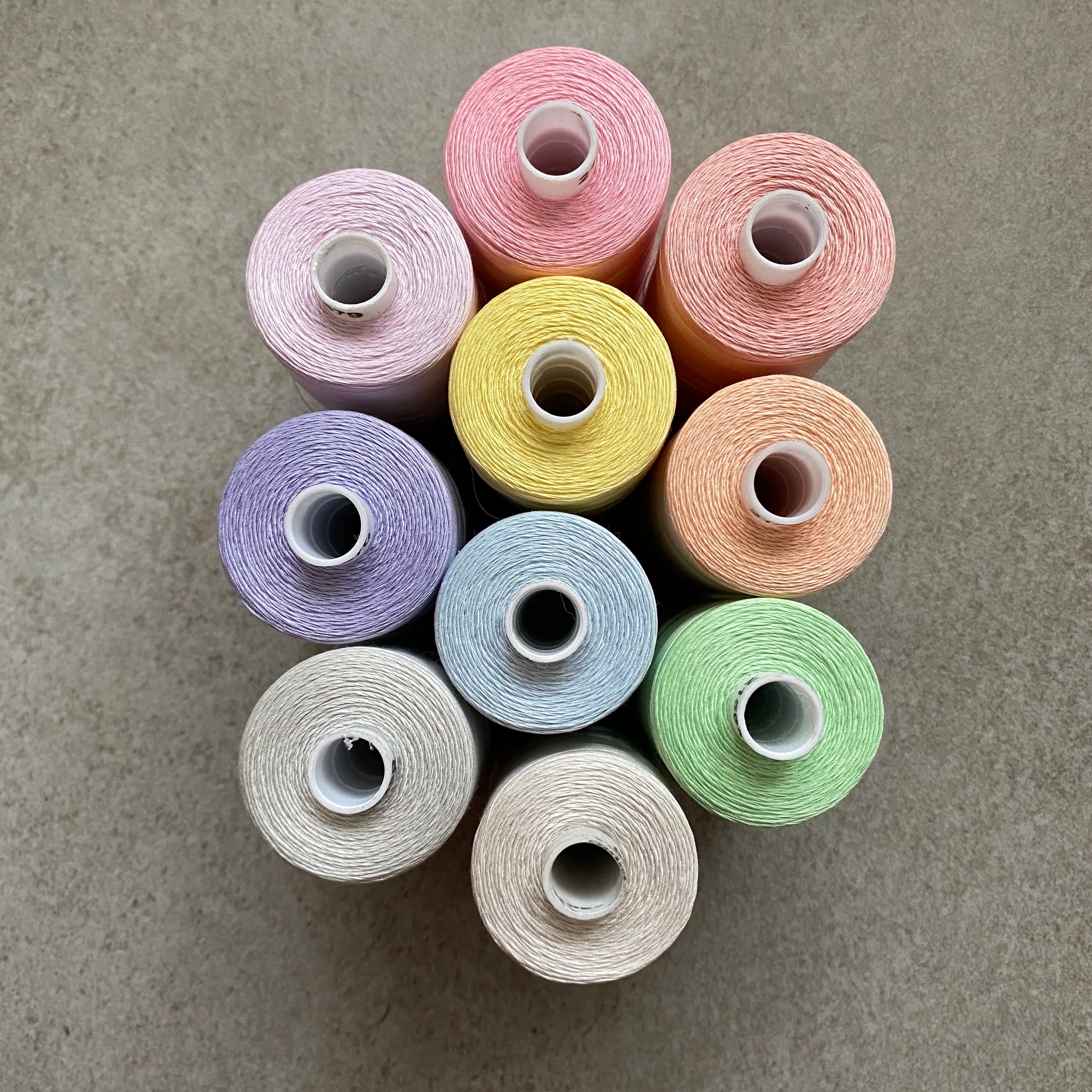 a photo of several spools of thread in multiple colors with a gray background